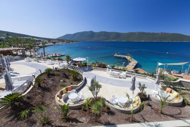 Ein Resort mit Blick auf das türkisfarbene Meer und eine bewaldete Küstenlinie.