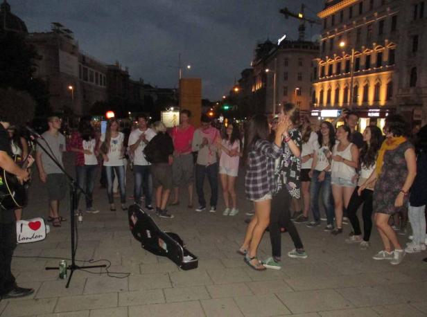 Eine Gruppe junger Leute tanzt zu Live-Musik auf einer Straße in der Stadt.