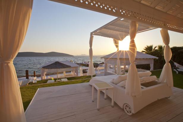 Ein luxuriöser Strandpavillon mit Blick auf das Meer bei Sonnenuntergang.