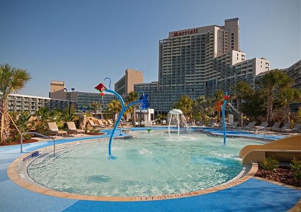 Ein flaches Becken mit Wasserspielen vor einem Marriott Hotel.