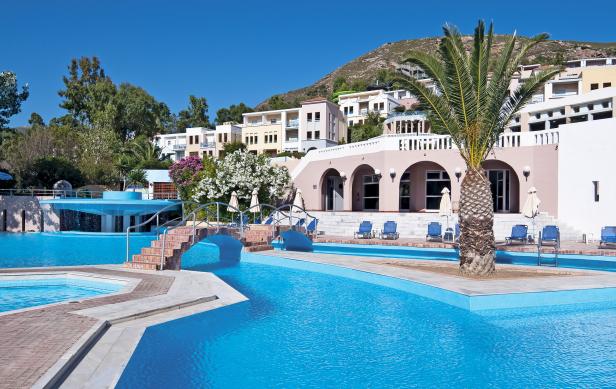 Ein Schwimmbad mit türkisfarbenem Wasser und einem Hotel im Hintergrund.