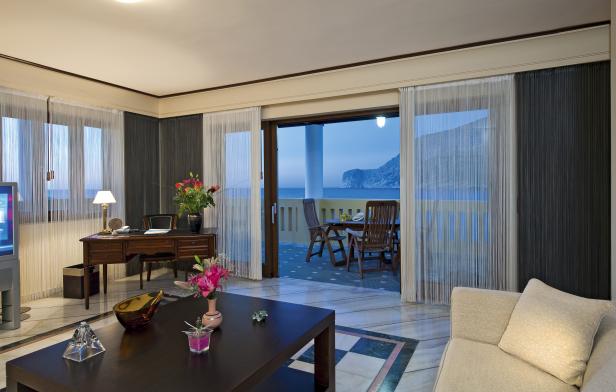 Ein Wohnzimmer mit Blick auf eine Terrasse mit Meerblick.