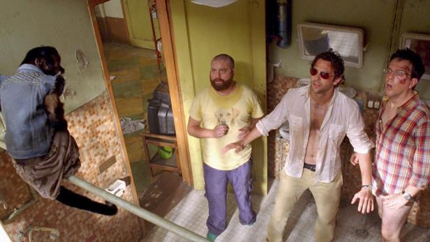 Alan, Phil und Stu aus „Hangover“ stehen verwirrt in einem Badezimmer, während ein Affe auf einem Rohr sitzt.