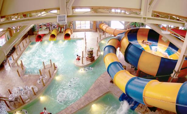 Blick in ein Hallenbad mit mehreren Wasserrutschen und einem Strömungskanal.