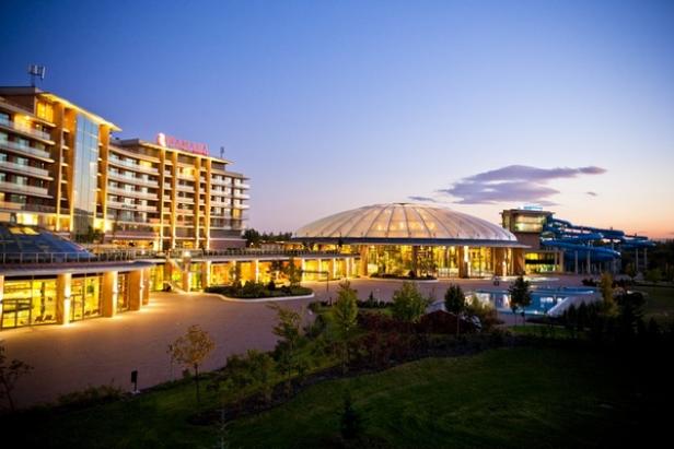 Das Ramada Hotel mit einem großen Kuppelbau und einer blauen Wasserrutsche im Hintergrund bei Dämmerung.