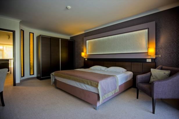 Ein Schlafzimmer mit Doppelbett, Sessel und dunklem Kleiderschrank.