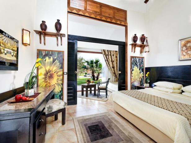 Ein helles Hotelzimmer mit offenem Zugang zu einer Terrasse und einem Garten.