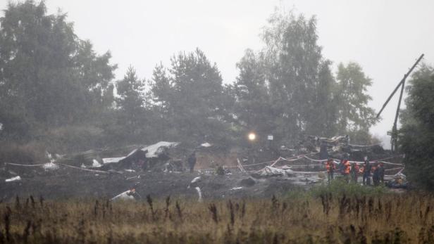 Rettungskräfte untersuchen die Trümmer eines Flugzeugabsturzes auf einem Feld.