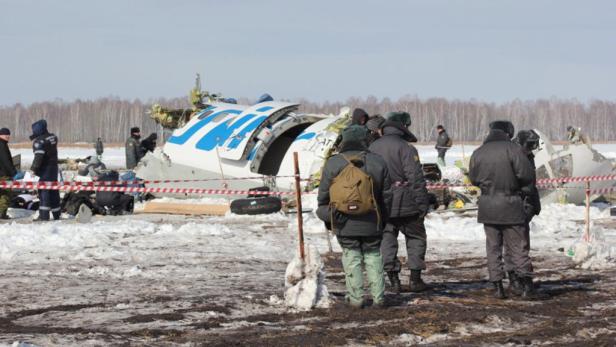 Einsatzkräfte stehen vor den Trümmern eines Flugzeugs auf einem schneebedeckten Feld.