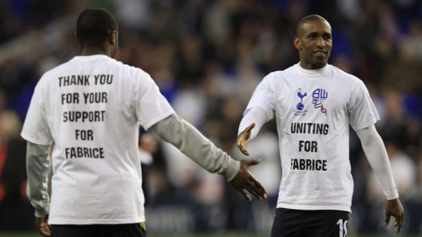 Fußballspieler tragen T-Shirts mit der Aufschrift „Thank you for your support for Fabrice“ und „Uniting for Fabrice“.