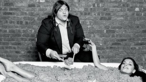 John Belushi serviert einer Frau in einer Wanne voller Popcorn Wein.