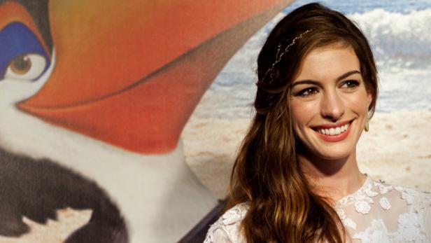 Anne Hathaway posiert vor einem Poster des Films „Rio 2“.