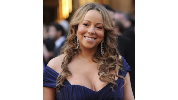 Mariah Carey lächelt in einem blauen Kleid mit baumelnden Ohrringen.