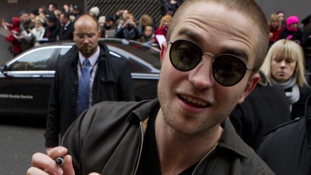 Robert Pattinson mit Sonnenbrille signiert Autogramme für Fans.