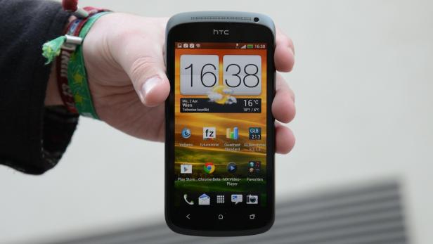 Eine Hand hält ein HTC-Smartphone, das 16:38 Uhr und teilweise bewölktes Wetter in Wien anzeigt.