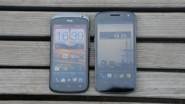 Zwei Smartphones, ein HTC und ein Google Nexus, liegen nebeneinander auf einer Holzoberfläche.