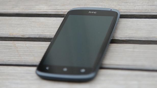 Ein HTC Smartphone liegt auf einem Holztisch.