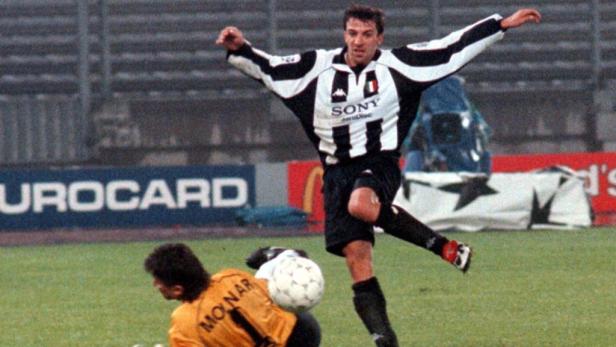 Ein Fußballspieler in einem schwarz-weiß gestreiften Trikot schießt auf das Tor.