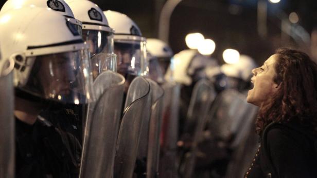 Eine Frau schreit eine Reihe von Polizisten mit Schutzschilden an.