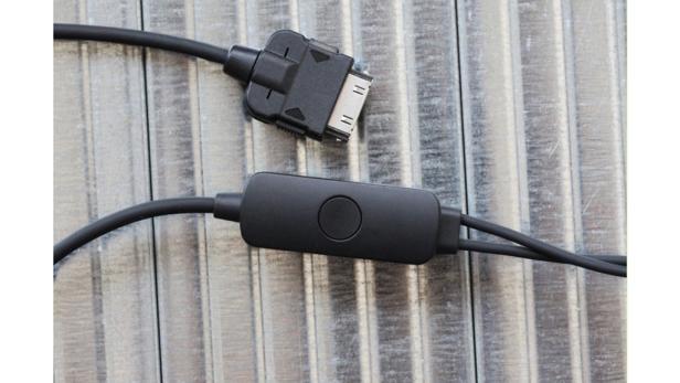 Ein schwarzes Kopfhörerkabel mit Stecker und Bedienelementen liegt auf einer geriffelten Oberfläche.