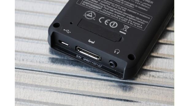 Die Unterseite eines schwarzen Geräts mit verschiedenen Anschlüssen und der Seriennummer QMN01Y0012Z.