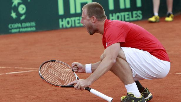 Ein Tennisspieler jubelt auf dem Platz mit geballter Faust und Tennisschläger.