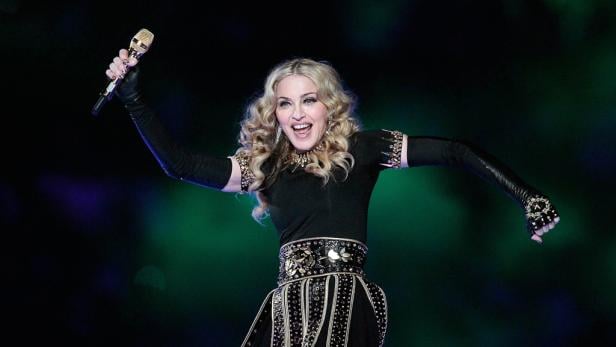 Madonna tritt während eines Konzerts mit einem goldenen Mikrofon in der Hand auf.