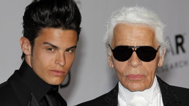 Karl Lagerfeld posiert mit einem jungen Mann auf einem Event.