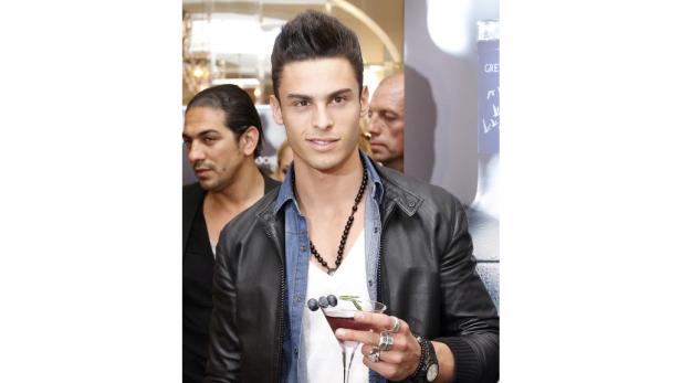 Ein Mann mit Lederjacke hält einen Cocktail mit Blaubeeren.