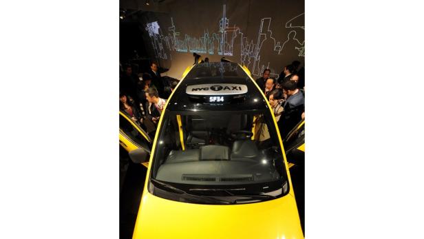 Ein gelbes NYC Taxi wird von Menschen auf einer Veranstaltung betrachtet.
