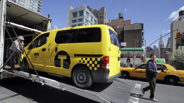 Ein gelbes Taxi wird von einem Arbeiter aus einem Lastwagen entladen.