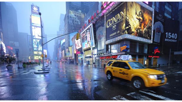 Ein gelbes Taxi fährt durch den verregneten Times Square in New York, mit Werbung für „Conan the Barbarian“.