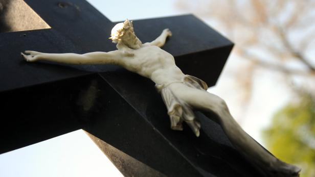 Eine Christusfigur hängt an einem schwarzen Kreuz.