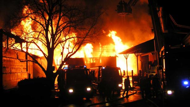 Ein Gebäude steht in Flammen, während Feuerwehrleute versuchen, das Feuer zu löschen.