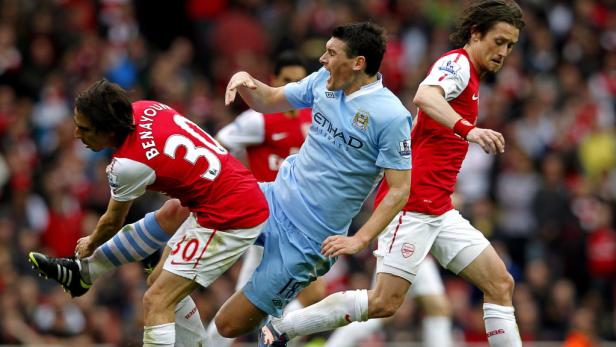Während eines Fußballspiels kämpfen Spieler von Arsenal und Manchester City um den Ball.