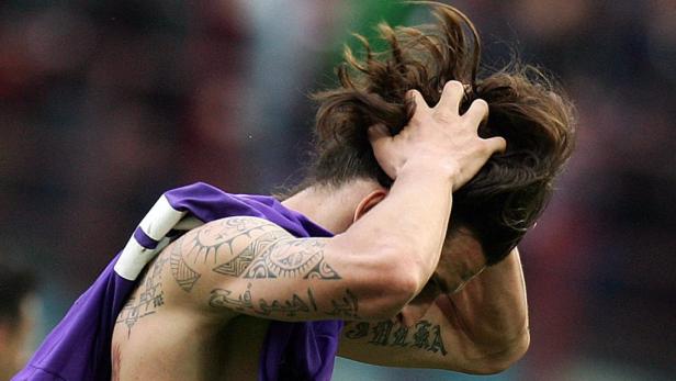 Ein Fußballspieler mit Tätowierungen fährt sich frustriert durch die Haare.