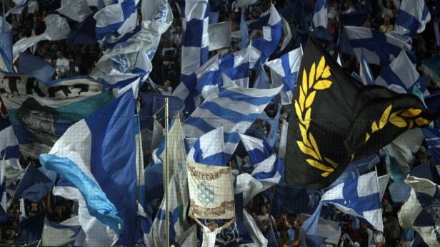 Eine Menschenmenge schwenkt blau-weiß gestreifte Fahnen und ein Banner mit einem Wappen.