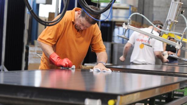 Ein Arbeiter reinigt eine große, glänzende Platte in einer Fabrikhalle.