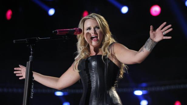 Miranda Lambert tritt in einem schwarzen Lederkleid auf einer Bühne auf.