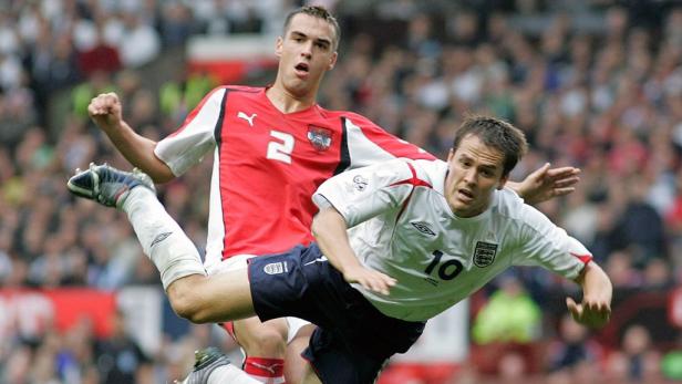 Ein österreichischer und ein englischer Fußballspieler kämpfen um den Ball.