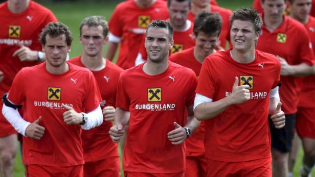 Eine Gruppe von Fußballspielern in roten Trikots gibt Daumen hoch.