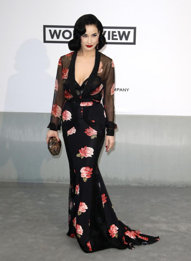 Dita Von Teese in einem langen, schwarzen Rosenkleid auf dem roten Teppich.