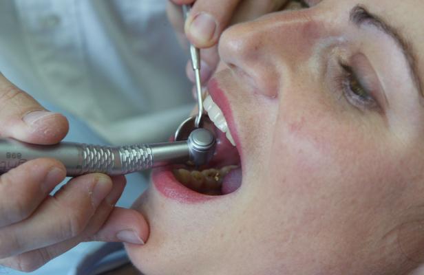 Eine Patientin wird von einem Zahnarzt mit einem Bohrer behandelt.