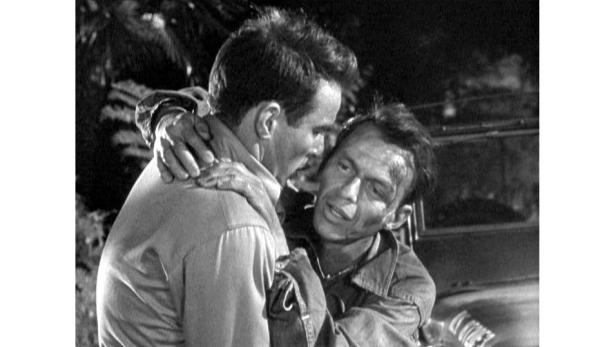 Zwei Männer umarmen sich; einer von ihnen ist schmutzig und scheint verletzt zu sein.