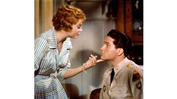 Szene mit Elvis Presley in Uniform und einer rothaarigen Frau.