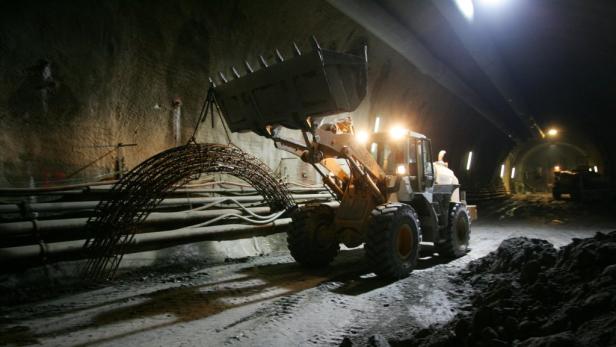 Ein Bagger transportiert eine Stahlkonstruktion in einem Tunnel.