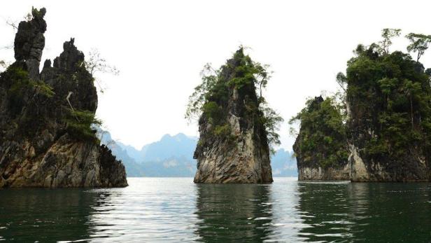 Bewachsene Kalksteinfelsen ragen aus dem ruhigen Wasser eines Sees.