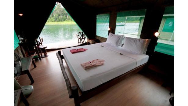 Ein Schlafzimmer mit Blick auf einen See in einer schwimmenden Unterkunft.