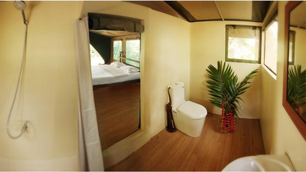 Ein Badezimmer mit Toilette und Blick in ein Schlafzimmer.