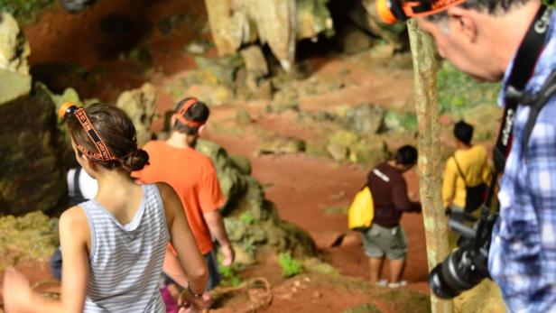 Eine Gruppe von Menschen erkundet eine Höhle mit Stirnlampen.